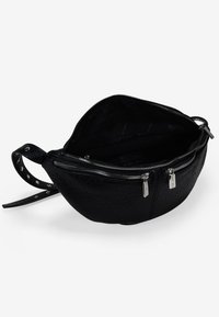 Bolso de cuero negro con un acabado texturizado, cierre de cremallera, bolsillo interior y detalle de tiras con tachuelas. Su forma es redondeada con una base plana.