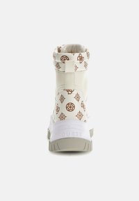 Zapatilla alta blanca con un cuello estampado, acentos del logo en marrón, suela de goma texturizada y una entresuela blanca sólida con branding.