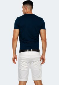 Navy short-sleeve shirt with a round neckline paired with white denim shorts. The shorts feature rolled cuffs and two back pockets.