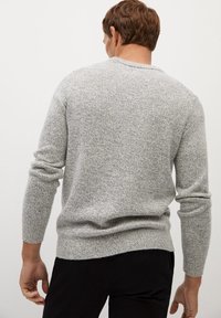 Pull en tricot texturé gris avec un col rond, des manches ajustées et une coupe légèrement ample au niveau de l'ourlet. Design simple sans motifs ni accents.