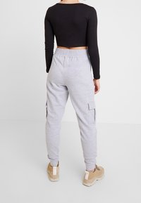 Szare dresy z elastycznym pasem i bocznymi kieszeniami, w połączeniu z czarnym, długim topem croppowanym. Obuwie w kolorze beżowym z masywną podeszwą.