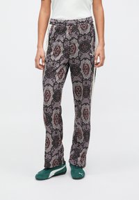 Παντελόνι σε χαλαρή γραμμή από υφασμάτινο σχέδιο. Γκρίζο φόντο με κόκκινους και μαύρους γεωμετρικούς σχεδιασμούς. Υφασμένο με ελαστική μέση.