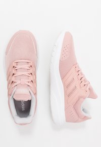 Zapatillas deportivas rosas con parte superior de malla, acentos sintéticos, lengüeta acolchada y suela de goma blanca. Presenta tres franjas en el lateral para mayor soporte.