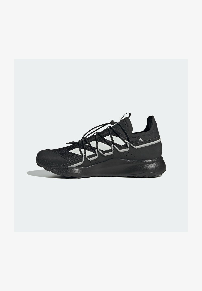 Černá sportovní bota s bílými akcenty, síťovaný svršek, elastické bungee šněrování a polstrovaná podrážka, zobrazená v bočním profilu na jednoduchém pozadí.
