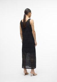 Vestido maxi de crochê preto com um design sem mangas, apresentando padrões intrincados e um corte solto, chegando abaixo das panturrilhas.