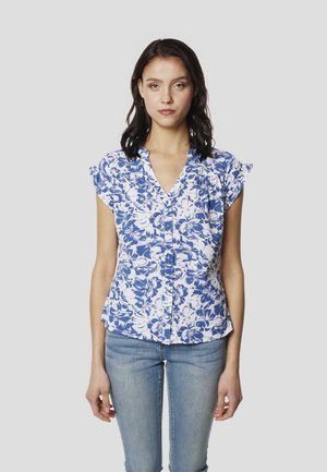 Blusa floral azul y blanca con mangas cortas con volantes, escote en v, cierre frontal con botones y dobladillo curvado. Se lleva con jeans ajustados.