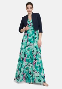 Długa kwiatowa sukienka w mieszance zieleni i różów, z dekoltem w serek i dopasowanym gorsetem. Połączona z usztywnioną granatową kurtką cropped.