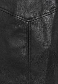 Svart konstlädertextur med en subtil ådring, med sömmar och ett chevronmönster i den övre sektionen.