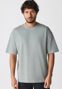 Lys grå t-shirt lavet af blødt bomuld, med en afslappet pasform, rund halsudskæring og korte ærmer med syede detaljer.
