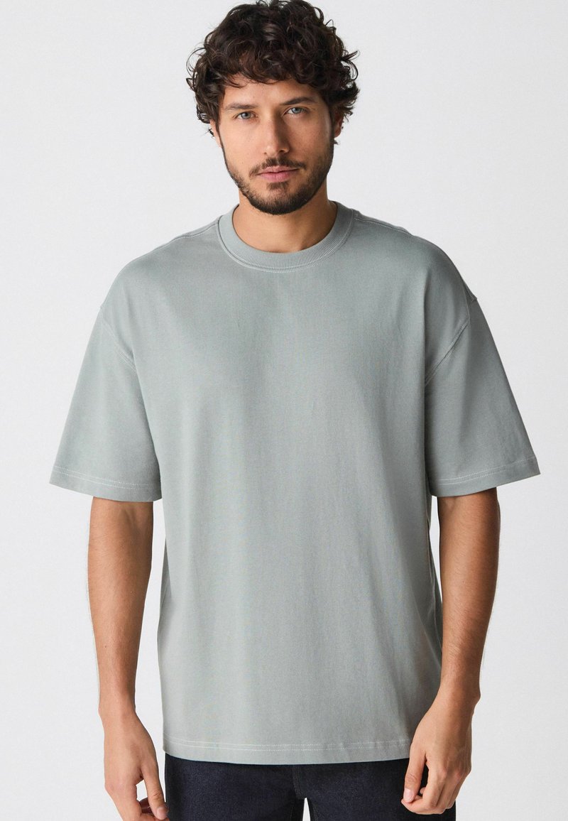 Lys grå t-shirt lavet af blødt bomuld, med en afslappet pasform, rund halsudskæring og korte ærmer med syede detaljer.