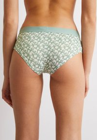 Sous-vêtements à imprimé floral vert avec une taille haute, dotés d'une ceinture lisse et d'une texture douce, conçus pour le confort et l'ajustement.