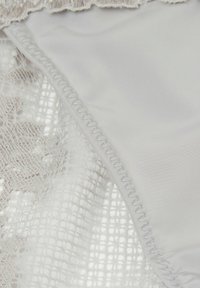 Bikini van kant en zachte stof, met een witte kleur, ingewikkeld kantpatroon en elastische randen, die textuur en effen materialen mengt.