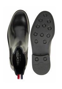 Crne kožne čizme do gležnja s elastičnim stranama, glatke završnice, zaobljenim prstima i potplatom od gume s uzorkom koji ima kružne gripove. Veličina 42.