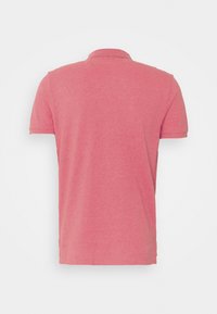 Vue de dos d'un polo rose uni à manches courtes avec col, présenté sur fond blanc.