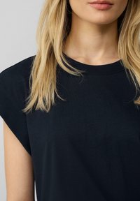 Tmavě námořnickomodré bavlněné tričko s krátkými, strukturovanými rukávy a kulatým výstřihem, s hladkou texturou a minimalistickým designem.