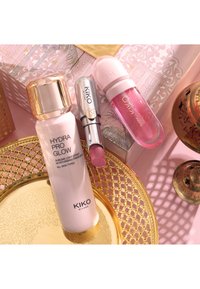 Krem nawilżający KIKO Milano Hydra Pro Glow, różowa szminka i różowy błyszczyk do ust ułożone na złotej tacy z wzorem na różowym dekoracyjnym tle.