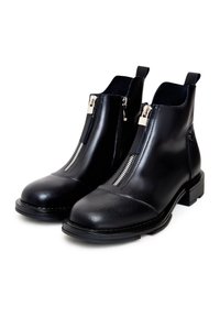 Bottes cheville en cuir noir avec fermetures éclair argentées sur le devant et languettes de tirage, dotées de talons blocs bas et d'orteils arrondis sur fond blanc.