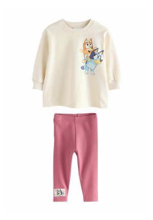 Crème sweatshirt met cartoonhonden, geribbelde boorden. Roze geribbelde leggings met een decoratieve hondenpatch op het onderbeen. Zacht materiaal.
