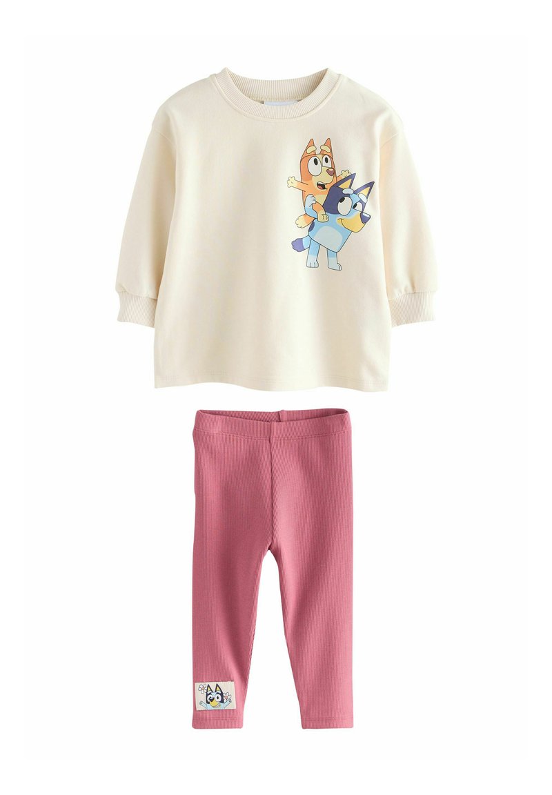 Felpa crema con cani cartone, maniche a costine. Leggings rosa a coste con una decorazione a forma di cane sulla gamba inferiore. Materiale morbido.