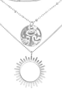 Gelaagde zilveren kettingen met een gestructureerde ronde hanger en een zonvormige hanger met spitse stralen, allemaal aan delicate kettingen.