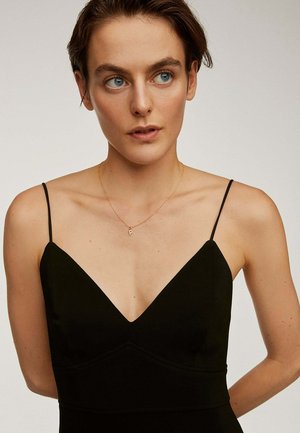 Vestido negro sin mangas con un escote en V profundo y un torso ajustado, hecho de una tela suave; presenta un sutil detalle de costura y tirantes delgados.
