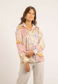 Chemise en soie avec un motif floral et cachemire dans des tons de rose, crème et jaune, dotée d'un col rabattu et de manches longues, amples.