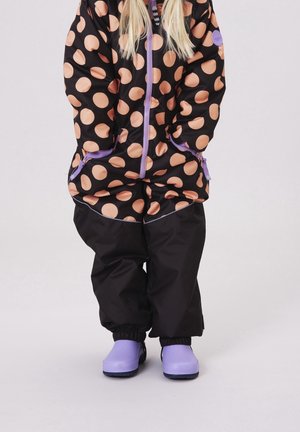 Sort vandtæt jakke med store ferskenfarvede polka prikker, lilla accenter og matchende lilla støvler. Bukser i ensfarvet sort med elastiske manchetter.