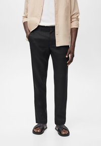 Black lightweight trousers with a straight cut, featuring a slight sheen and side pockets, paired with flat black sandals.