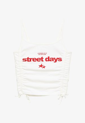 Bijela nabrana majica s tankim naramenicama, crveni tekst "gledajući u nebo gradske ulice" i dvije crvene zvijezde ispod teksta.