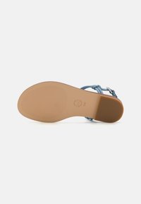 Sandale de culoare albastru deschis, cu un design de curea împletită, având o talpă netedă și un fund texturat pentru aderență. Include accesorii cu cataramă.