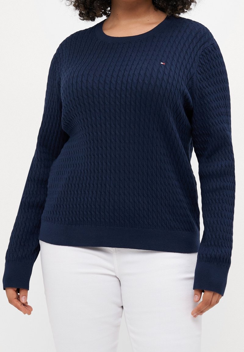 Maglione a maglia blu navy con motivo a diamante testurizzato, collo a giro e polsini a costine. I loghi presenti sul petto sono piccoli e discreti.