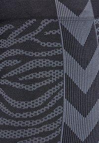 Prestationsleggings i svart med grå geometriska mönster, med varierande texturer och en räfflad design längs midjan och benen.