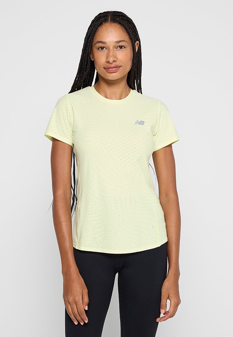 Kurzärmeliges, hellgelbes Sport-T-Shirt aus strukturiertem Stoff mit einem kleinen grauen Logo auf der Brust, kombiniert mit schwarzen Leggings.