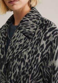 Cappotto con stampa animale, base grigia e macchie leopardate nere, dotato di colletto a punta e tessuto morbido e testurizzato.