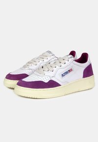 Sneakers bianche con accenti in camoscio viola, dotate di punta perforata, suola in gomma testurizzata e lacci beige. Logo del marchio visibile sul lato.
