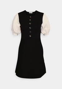 Robe noire avec des manches bouffantes blanches, un col à festons et des boutons décoratifs en or sur le devant.
