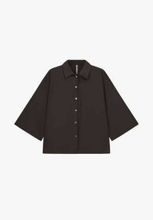 Chemise noire à manches longues boutonnée, avec un col pointu et des manches larges, présentée à plat sur fond blanc.