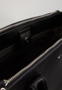 Borsa a mano in pelle nera con zip argentata, spazioso interno e chiusura a scatto magnetica, dotata di tasca interna con zip e superficie liscia.