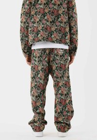 Conjunto de ropa de casa con estampado floral que presenta un corte suelto y holgado. El material es suave, con un fondo verde oscuro y diseños de flores multicolores.
