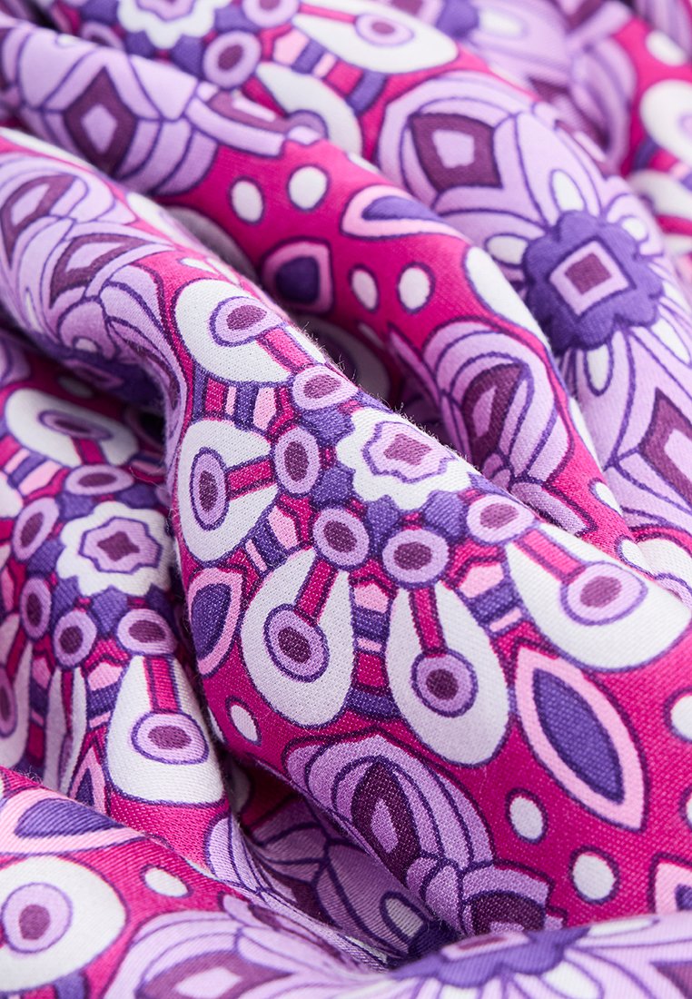 Tissu coloré avec un motif géométrique audacieux comprenant des nuances de rose et de violet, texture lisse, et motifs floraux et circulaires contrastés.