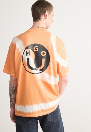 Tie-dye orange shirt featuring a large black graphic logo on the back. Short sleeves and a relaxed fit, with a soft cotton texture.