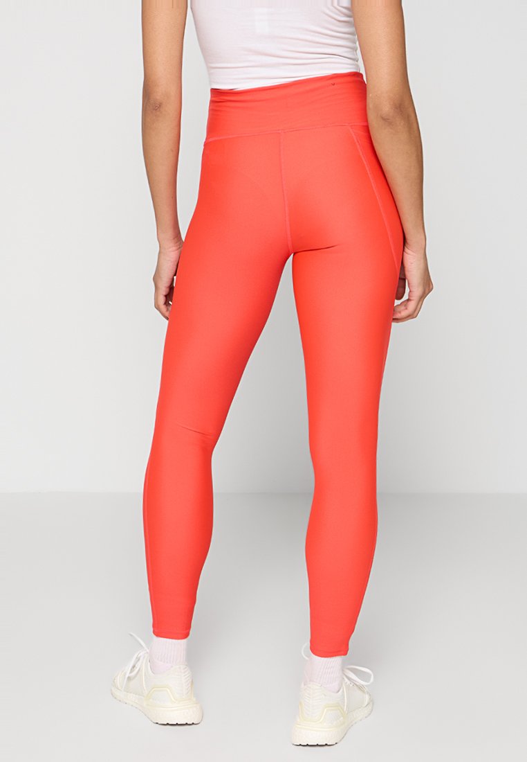 Leggings de cintura alta y ajuste ceñido en un brillante color coral, confeccionados en un material elástico, con una textura suave y sin patrones visibles.