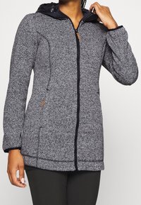 Giacca grigia con texture a zip, dotata di cappuccio scuro, munita di tasche laterali e dettagli neri a contrasto lungo la zip e i polsini.