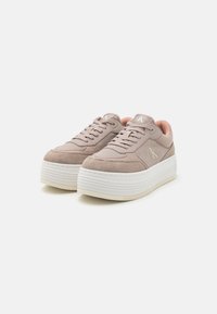 Sneaker Calvin Klein con tomaia in suede beige e morbida, dotate di suole a piattaforma bianche, lacci rotondi e un piccolo accento con il logo.