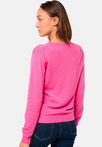 Pull rose avec encolure ras du cou, manches longues, poignets et ourlet côtelés. Texture douce, silhouette légèrement ajustée, longueur standard.