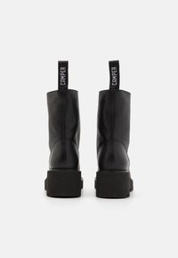 Black leather ankle boots with a chunky black platform sole. Features a pull tab with "CAMPER" branding on the back. Smooth texture.