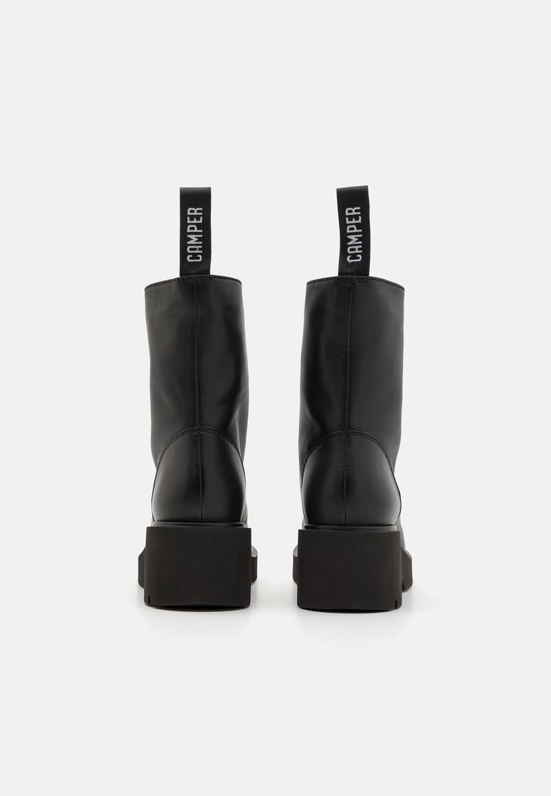 Schwarze Lederstiefeletten mit einer klobigen, schwarzen Plateausohle. Mit einer Zuglasche mit "CAMPER"-Branding auf der Rückseite. Glatte Textur.