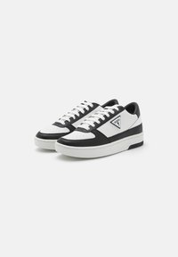 Sneaker basse in bianco e nero realizzate in pelle liscia, con punta perforata, dettagli testurizzati e logo sul lato.