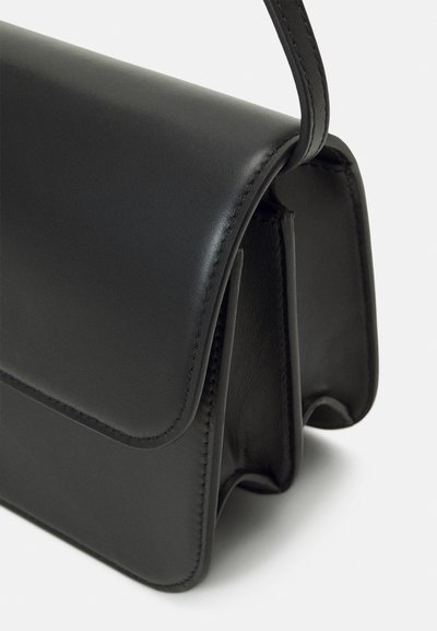 Čierna kožená kabelka so štruktúrovaným tvarom, so hladkým povrchom, preklápacou chlopňou a detailným prešívaním.