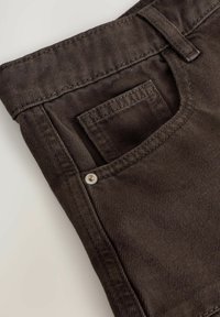 Tmavě hnědé džínsy z denimu s přední kapsou a kovovým detailem knoflíku. Textura je hladká s mírným leskem.